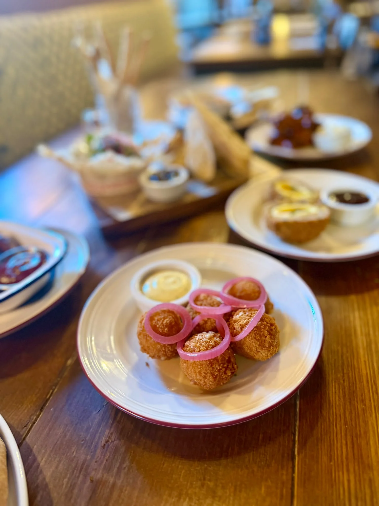 Breaded bites topped with pickled red onion rings and served with a dip