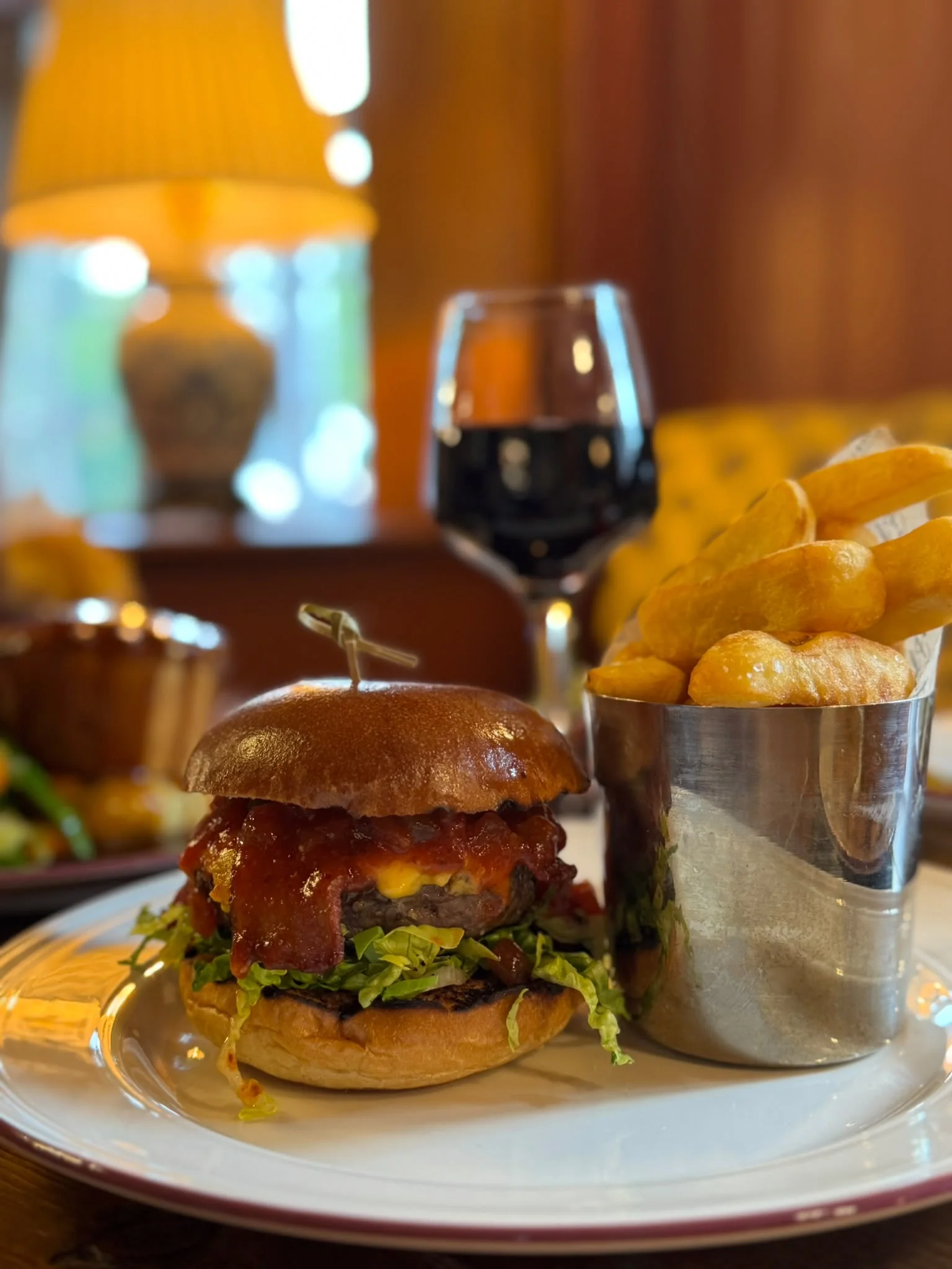 A burger served with chips beside a glass of red wine