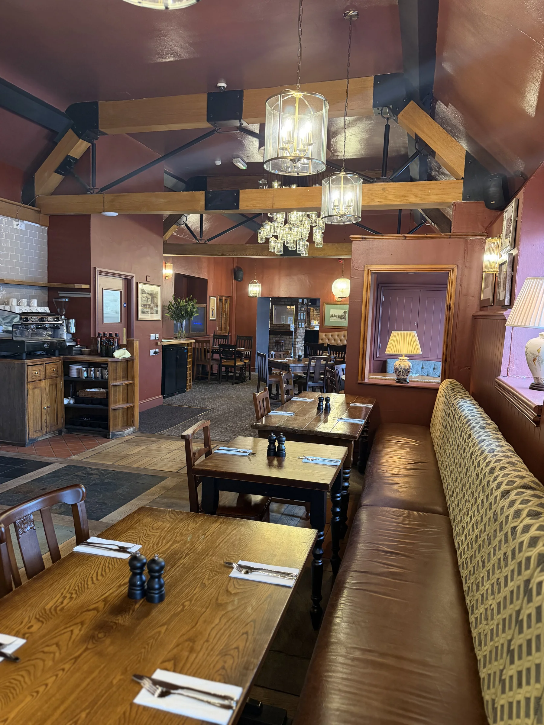Dining tables and bench seating beneath chandeliers