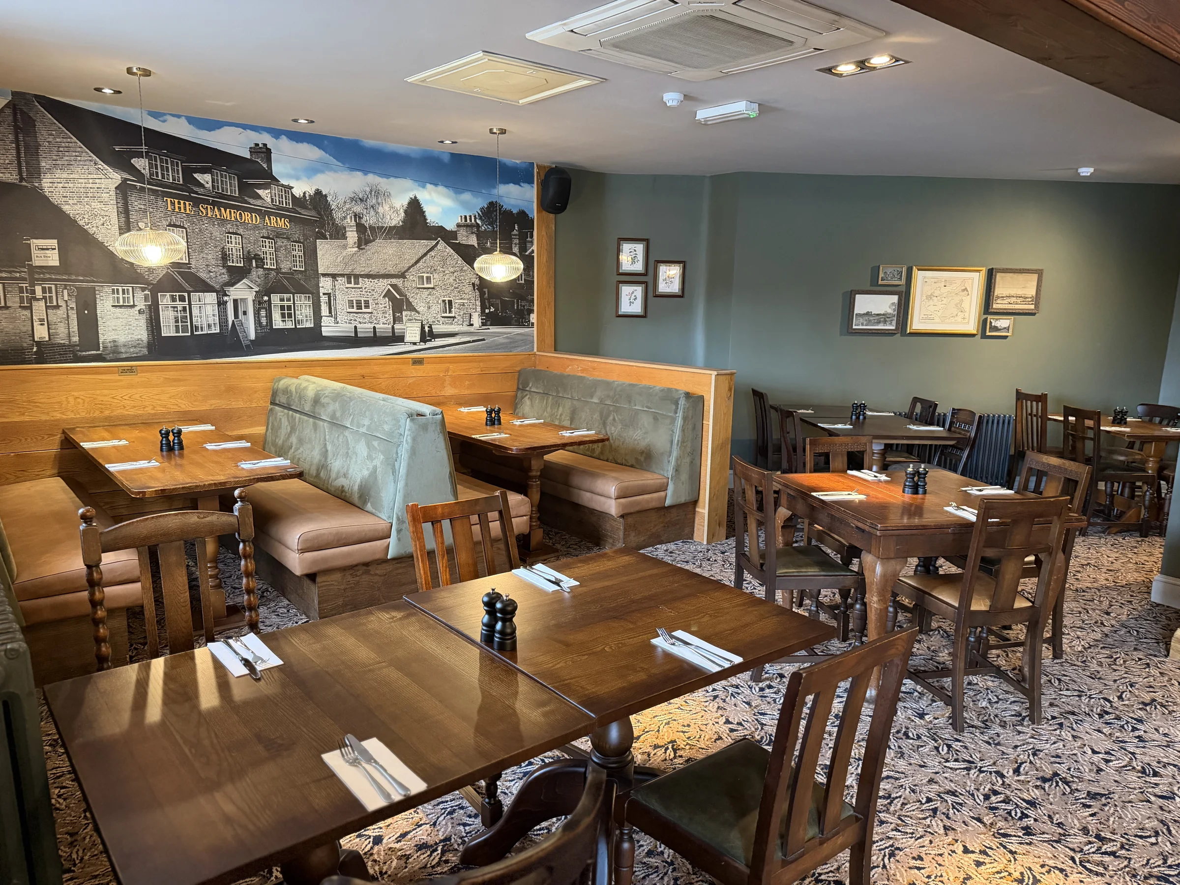 Dining tables and booth seating beneath a village mural